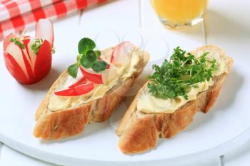 Slices of baguette with butter, radish and cress