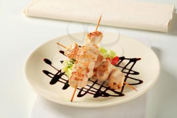 Chicken skewers garnished with balsamic vinegar drizzle