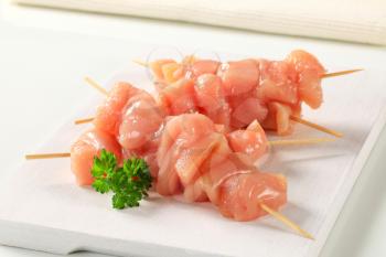 Raw chicken cubes on wooden skewers