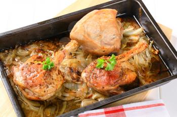 Roast duck legs with caraway and onion in a baking pan