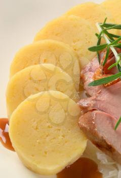 Dish of pork meat with potato dumplings and white cabbage