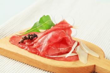 Thinly sliced raw beef meat on cutting board