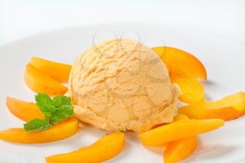 Scoop of ice cream with slices of fresh apricot