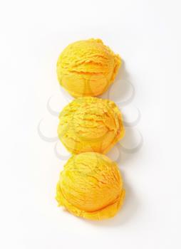 Three scoops of yellow ice cream arranged in a row