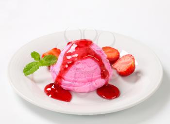 Scoop of pink ice cream with strawberry sauce