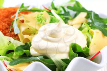 Green salad with fried breaded cheese and sliced Swiss cheese and mayonnaise