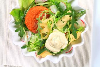Green salad with fried breaded cheese and sliced Swiss cheese and mayonnaise