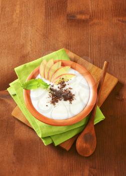 Bowl of milk pudding with apple slices and grated chocolate