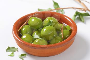 Bowl of green olives in oil