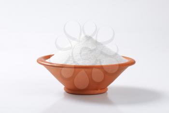 Heap of white sugar in terracotta bowl