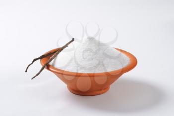 Bowl of white granulated sugar and two dried vanilla beans