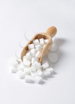 White sugar cubes in wooden scoop
