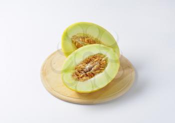 Two yellow melon halves on cutting board