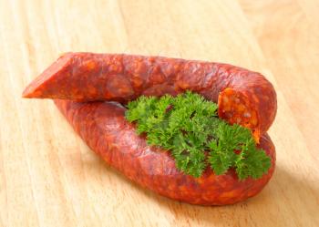 Spicy dry sausages on wooden background