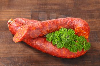 Spicy dry sausages on wooden background