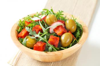 Salad greens with  green olives and diced paprika-coated cheese 