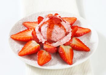 Fresh strawberries arranged around scoop of pink ice cream
