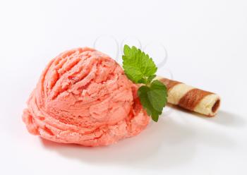 Scoop of pink fruit sherbet and chocolate wafer curl