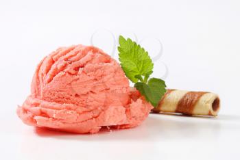 Scoop of pink fruit sherbet and chocolate wafer curl