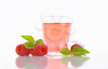 Glass of raspberry-flavored drink and fresh raspberries