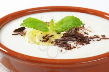 Bowl of smooth milk pudding with sliced banana and grated chocolate