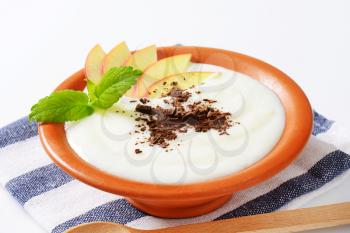 Bowl of milk pudding with apple slices and grated chocolate