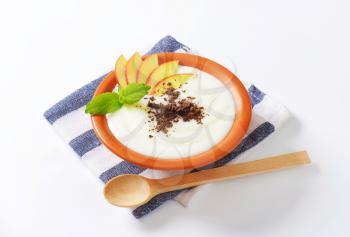 Bowl of milk pudding with apple slices and grated chocolate