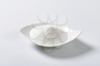 Heap of crystal sugar in white bowl