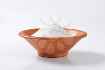 Heap of white sugar in terracotta bowl