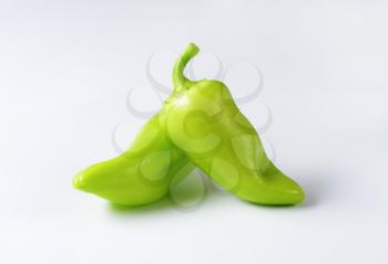 Two green peppers on white background