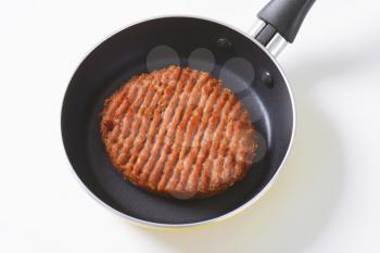 Pan-fried beef burger patty in pan