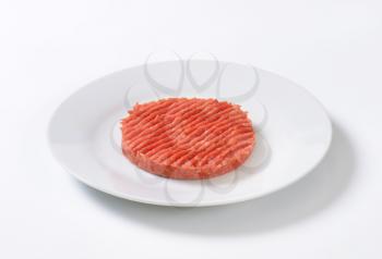 raw hamburger patty on white plate