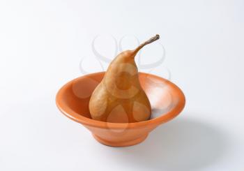 Ripe Bosc pear in a terracotta bowl