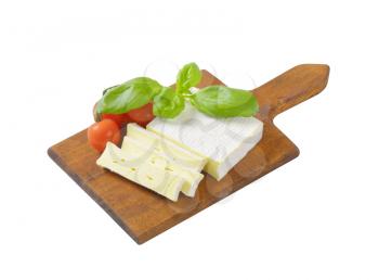 Sliced soft cow's milk cheese on cutting board