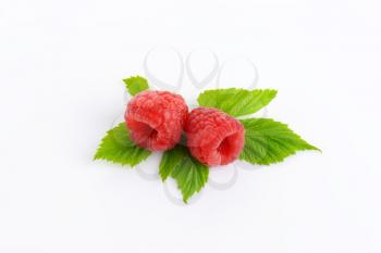 Fresh raspberries with leaves on white background