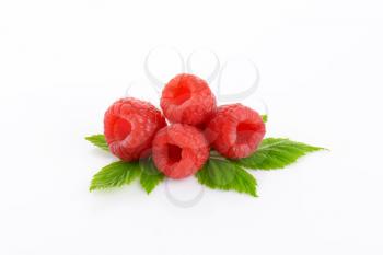 Fresh raspberries with leaves on white background