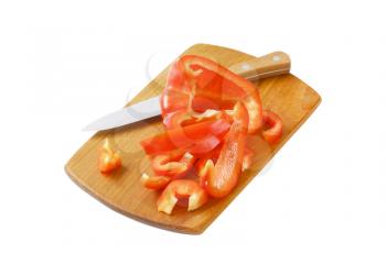 sliced red bell pepper and kitchen knife on wooden cutting board