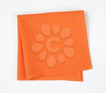 Folded orange napkin on white background