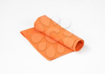 Rolled orange  napkin on white background