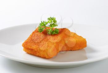two pieces of fried fish with fresh parsley on white plate