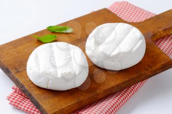two wheels of soft creamy cheese with white mold
