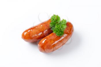 two fried sausages with parsley on white background