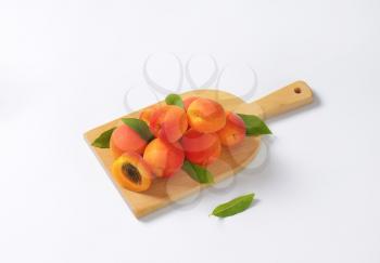 Heap of ripe apricots on wooden cutting board