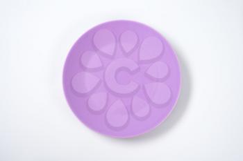 empty violet plate on off-white background