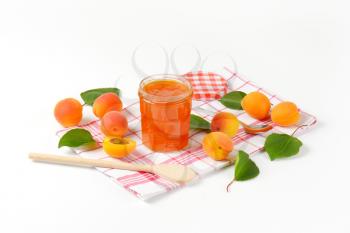 Jar of apricot jam and fresh apricots on checked tea towel
