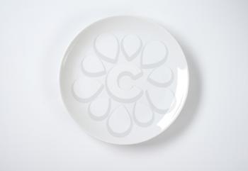 empty rimless white plate on off-white background