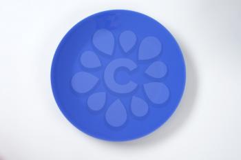 empty blue dinner plate on off-white background