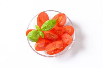 Halved oblong red tomatoes on glass plate