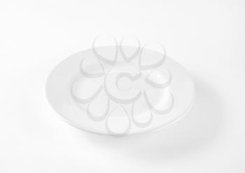 Empty white porcelain dinner plate with rolled edge