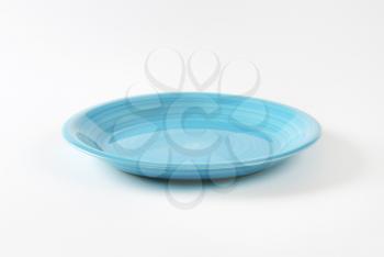 Coup shaped ceramic plate with a blue color glaze